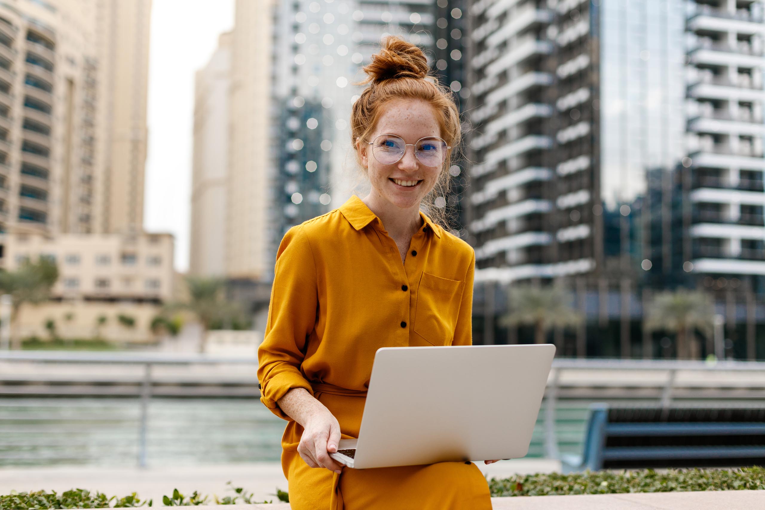 young student sitting in Dubai Marina area with an open laptop