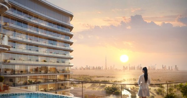 woman on balcony with dubai skyline sunset